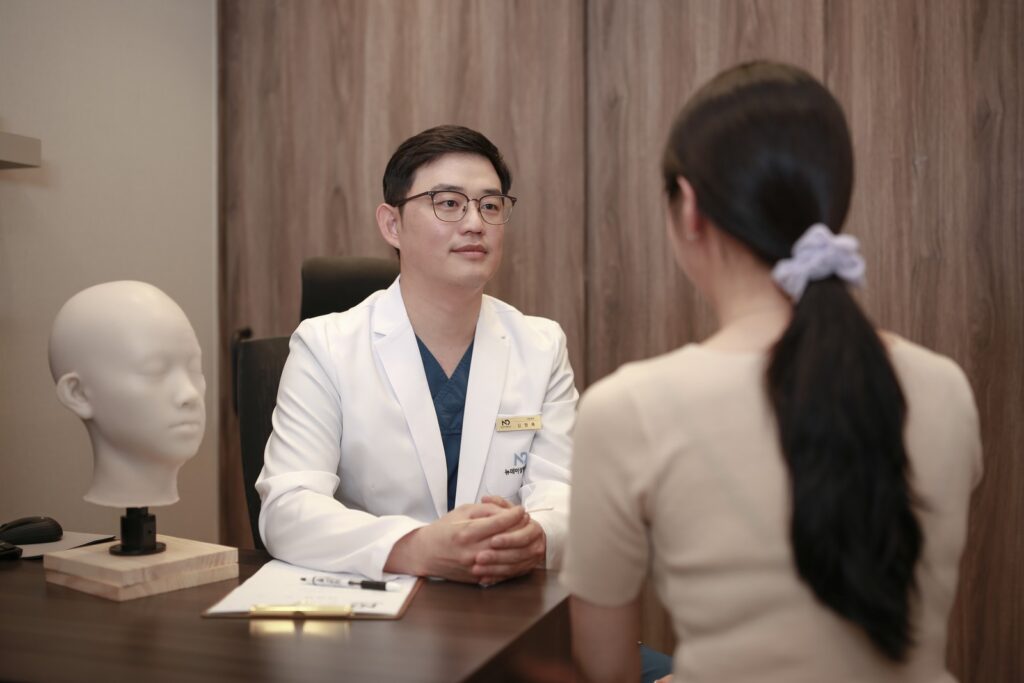 논현역 뉴데이성형외과 진료실에서 원장이 환자와 마주 앉아 상담하는 장면