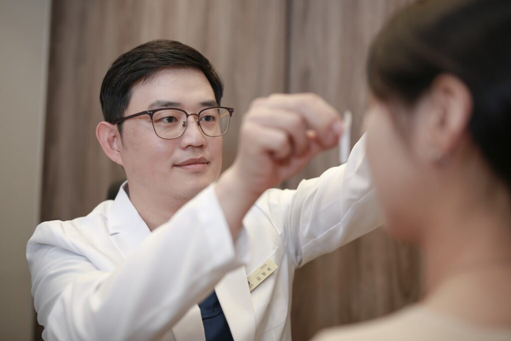 논현역 뉴데이성형외과 원장이 기구를 들고 환자의 눈가를 살피는 상담 장면